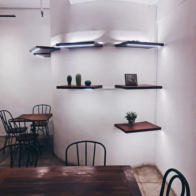 A daylit corner of the cafe with oak tables and floating shelves